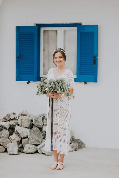 Yunanistan 'ın Santorini adasında, popüler bir düğün merkezi olan mavi pencereli beyaz mimarinin arka planında güzel bir gelin. — Stok fotoğraf