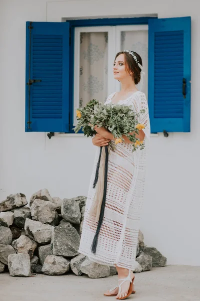 Hermosa novia en un fondo de arquitectura blanca con ventana azul en la isla de Santorini, Grecia, un destino de boda popular — Foto de Stock