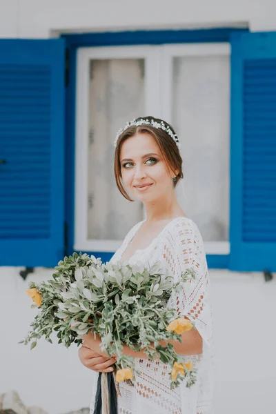Krásná nevěsta na pozadí bílé architektury s modrým oknem na ostrově Santorini, Řecko, populární svatební destinace — Stock fotografie