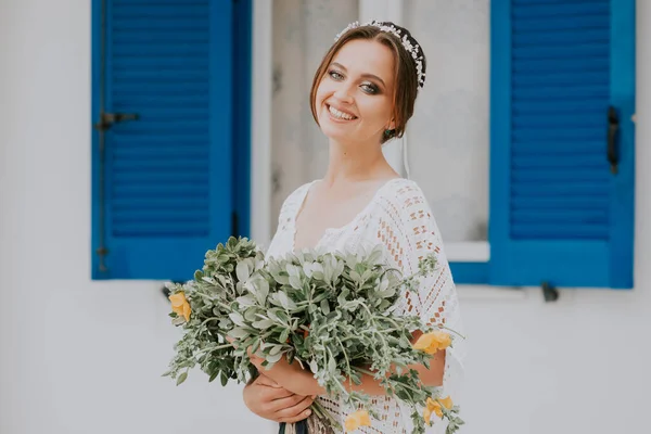 Yunanistan 'ın Santorini adasında, popüler bir düğün merkezi olan mavi pencereli beyaz mimarinin arka planında güzel bir gelin. — Stok fotoğraf