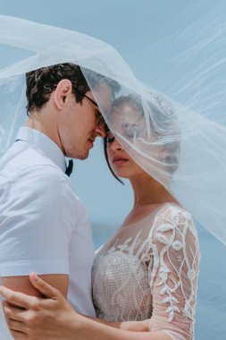 Güzel gelin ve damat, Yunanistan 'ın Santorini adasındaki düğün günlerinde gelin peçesinin altında sarılıp öpüşüyorlar.