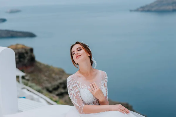 흰옷을 입은 낭만적 이고 아름다운 신부 가 바다 와산을 배경으로 계단식으로 누워 있다 — 스톡 사진