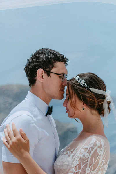 Mooie bruid en bruidegom knuffelen en kussen onder de bruidssluier in hun zomer trouwdag op het Griekse eiland Santorini — Stockfoto