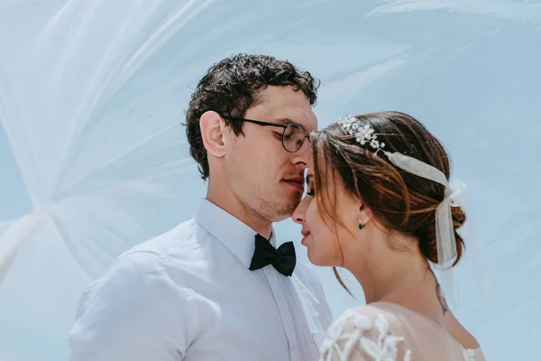 Bela noiva e noivo abraçando e beijando sob o véu nupcial em seu dia de casamento de verão na ilha grega Santorini — Fotografia de Stock