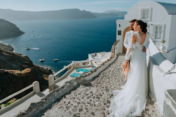 Gyönyörű menyasszony és vőlegény a nyári esküvő napján a görög Santorini szigeten — Stock Fotó