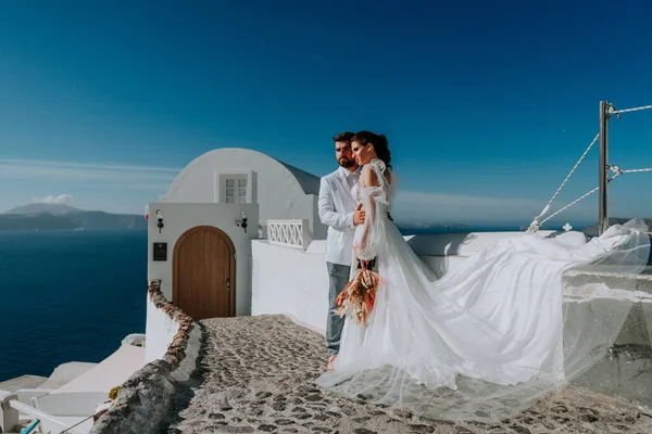 Gyönyörű menyasszony és vőlegény a nyári esküvő napján a görög Santorini szigeten — Stock Fotó