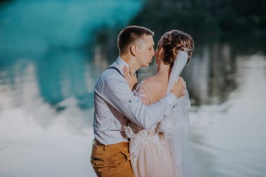 Gelin ve damat, yaz parkında mavi ve sarı renkli sis bombalarıyla. Gelin ve damat, yaz ormanının arka planında renkli dumanlarla. Düğün çifti renkli sigara içiyor.