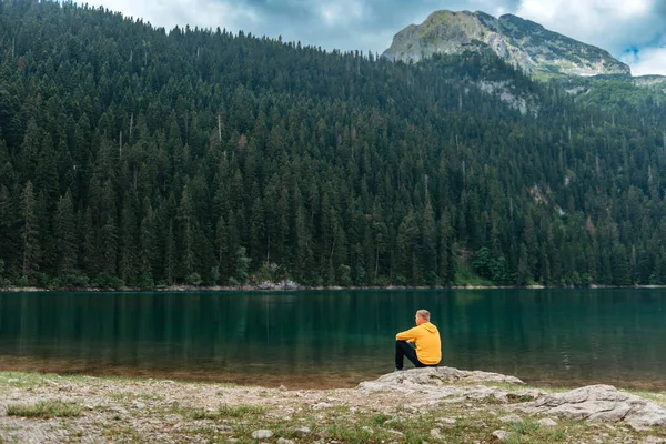 Traveler Man meditação relaxante com serena vista montanhas e paisagem do lago. Viagens Estilo de vida caminhadas conceito férias de verão ao ar livre. Um tipo perto do lago da montanha. Um homem solitário olha em frente — Fotografia de Stock