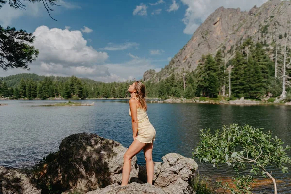 관광객들은 산에 있는 청록색 호수의 바닷가에 있는 큰 돌 위에 있는 호수, 울창 한 숲, 마법같은 경치를 즐긴다. 자연사 공원에서 하이킹하는 거요. 귀여운 소녀 — 스톡 사진