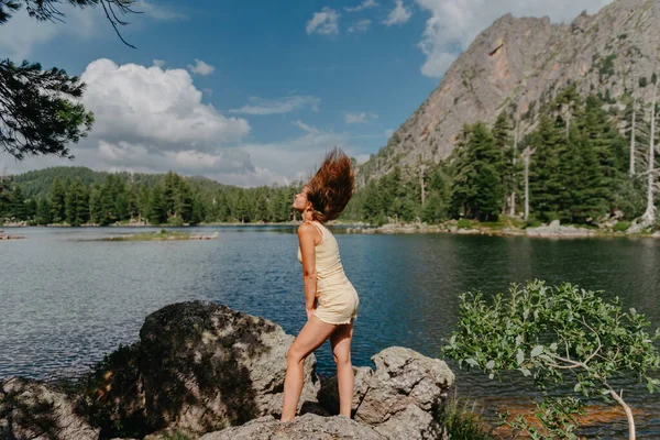 관광객들은 산에 있는 청록색 호수의 바닷가에 있는 큰 돌 위에 있는 호수, 울창 한 숲, 마법같은 경치를 즐긴다. 자연사 공원에서 하이킹하는 거요. 귀여운 소녀 — 스톡 사진