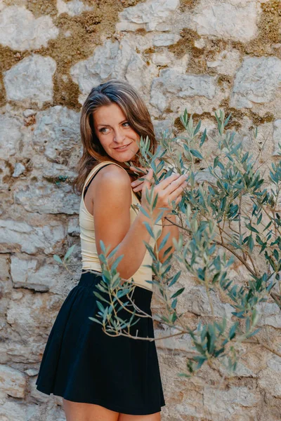 Flicka turist promenader genom antika smala gatan på en vacker sommardag i MEDITERRANEAN MEDIEVAL stad, OLD TOWN BUDVA, MONTENEGRO. Ung vacker glad kvinna promenader på gamla gatan på — Stockfoto