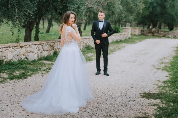 Felice elegante coppia sorridente passeggiando in Toscana, Italia il giorno del loro matrimonio. Gli sposi camminano per strada per le mani. Una giovane coppia elegante cammina. Marito e moglie comunicano bene — Foto Stock