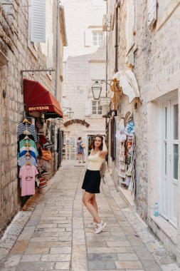 MEDITERRANEAN MEDİEVAL ŞEHRİ, OLD TOWN BUDVA, MONTENEGRO 'DA Güzel bir Yaz Günü' nde Antik Narrow Caddesi 'nde Yürüyen Kız Turist. Genç, güzel, neşeli bir kadın Old Street 'te yürüyor.