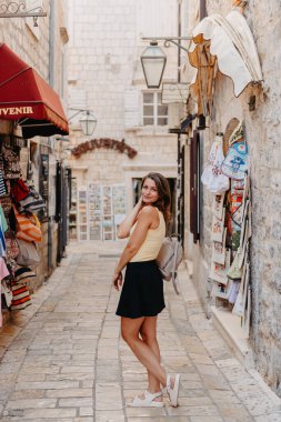 MEDITERRANEAN MEDİEVAL ŞEHRİ, OLD TOWN BUDVA, MONTENEGRO 'DA Güzel bir Yaz Günü' nde Antik Narrow Caddesi 'nde Yürüyen Kız Turist. Genç, güzel, neşeli bir kadın Old Street 'te yürüyor.