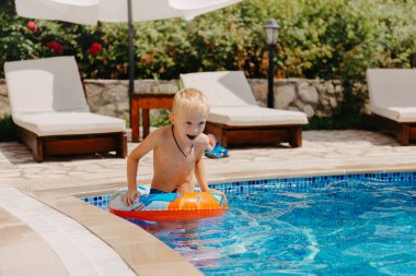 Mutlu çocuk yaz tatilinde eğleniyor. Çocuk denizde lastik ördek ve topla oynuyor. Sağlıklı yaşam tarzı kavramı. Mutlu çocuk yüzme havuzunda oynuyor. Yaz tatilleri konsepti