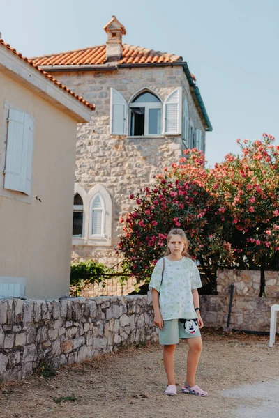 Chica turística caminando por la antigua calle estrecha en un hermoso día de verano en MEDITERRÁNEO MEDIEVAL CITY, BUDVA ANTIGUA, MONTENEGRO. Joven hermosa alegre adolescente chica caminando en viejo calle en — Foto de Stock