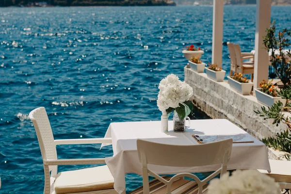 Pemandangan jalanan teras tepi laut terbuka dengan meja dan kursi di restoran di desa bersejarah Perast di Kotor Bay, Montenegro. Konsep tujuan liburan musim panas — Stok Foto