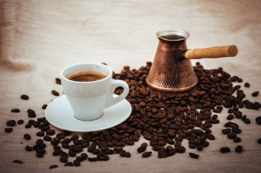 Çuval bezi üzerine kahve ve Türk kahvesi. Beyaz arka planda izole kahve çekirdekleri. Kavrulmuş kahve çekirdeği.