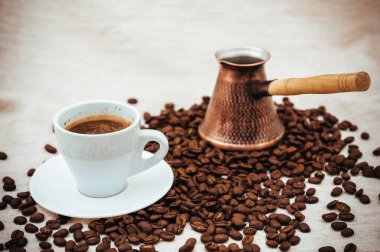 Çuval bezi üzerine kahve ve Türk kahvesi. Beyaz arka planda izole kahve çekirdekleri. Kavrulmuş kahve çekirdeği.