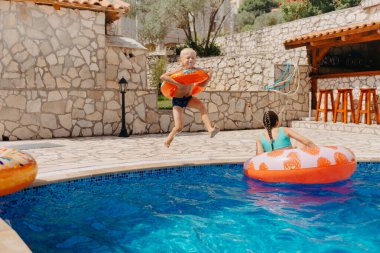 Mutlu çocuk yaz tatilinde eğleniyor. Çocuk denizde lastik ördek ve topla oynuyor. Sağlıklı yaşam tarzı kavramı. Mutlu çocuk yüzme havuzunda oynuyor. Yaz tatilleri konsepti