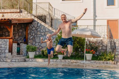 Google 'da heyecanlı bir çocuk babasının yüzme havuzunda duran omuzlarından suya atlıyor.