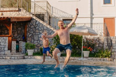 Google 'da heyecanlı bir çocuk babasının yüzme havuzunda duran omuzlarından suya atlıyor.