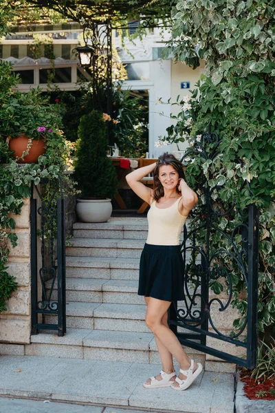 Flicka turist promenader genom antika smala gatan på en vacker sommardag i MEDITERRANEAN MEDIEVAL stad, OLD TOWN BUDVA, MONTENEGRO. Ung vacker glad kvinna promenader på gamla gatan på — Stockfoto