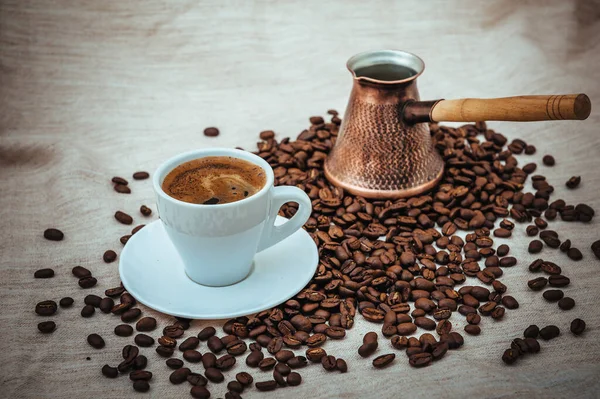 Turk café e xícara de café no fundo da serapilheira. grãos de café isolados em fundo branco. torrado grãos de café — Fotografia de Stock