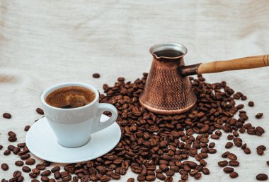 Çuval bezi üzerine kahve ve Türk kahvesi. Beyaz arka planda izole kahve çekirdekleri. Kavrulmuş kahve çekirdeği.