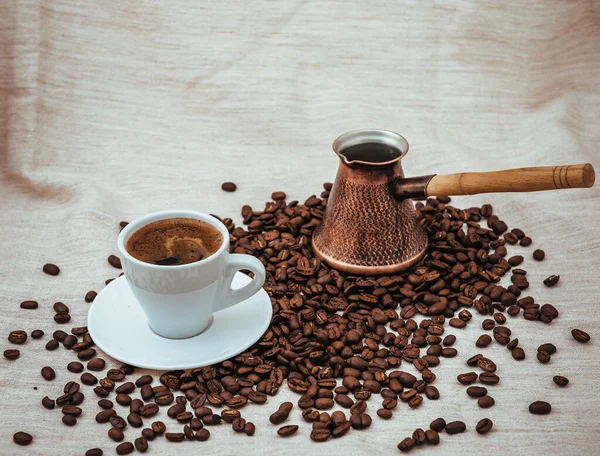 Kaffee-Türke und Tasse Kaffee auf Klett-Hintergrund. Kaffeebohnen isoliert auf weißem Hintergrund. geröstete Kaffeebohnen — Stockfoto