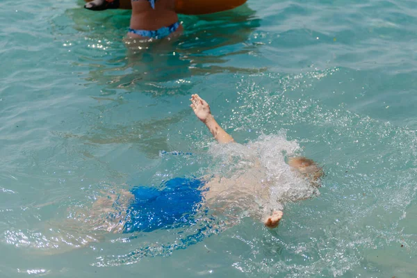 Child learning to swim in the open sea of tropical resort. Kids learn swimming. Exercise and training for young children. Little boy with colorful float board in sport club. Swimming baby or toddler