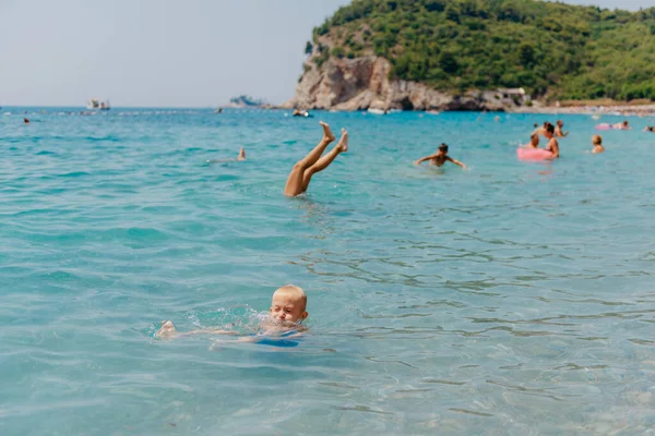 Child learning to swim in the open sea of tropical resort. Kids learn swimming. Exercise and training for young children. Little boy with colorful float board in sport club. Swimming baby or toddler