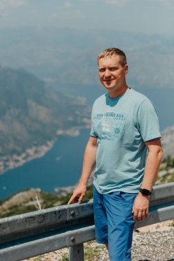 Erkek turist Kotor 'un manzarasından hoşlanıyor. Karadağ. Kotor Körfezi, Kotor Körfezi, Boka Kotorska ve eski şehrin duvarları. Karadağ 'a seyahat. Kotor 'un tahkimatları UNESCO Dünya Mirası' nda