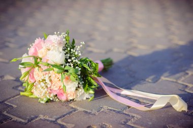 Çiçeklerin düğün buketi. Sarı ve beyaz güllerden oluşan düğün buketi beton zeminde yatıyor..