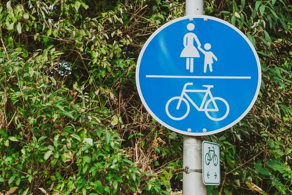 german sign Sidewalk with bike path. blue background with pedestrian and bicycle. Dutch blue Traffic sign with green leaves. Road sign path for bicycles and walks with children