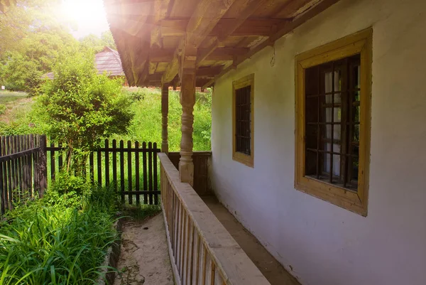 春または夏の典型的なウクライナの風景 藁屋根と前景に木の白い粘土小屋 — ストック写真