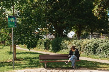 Sokakta bankta oturan akıllı telefonu kullanan mutlu bir kız. Güzel bir kız bankta oturuyor. Moda hayatı tarzında. Telefonunla sosyal ağlara bir mesaj yazıyor.