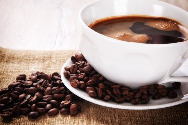 kahve fincanı ve tabağı bir çuval bezi üzerinde kahve çekirdekleri ile