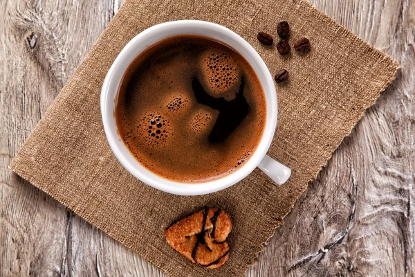 Coffee cup with coffee beans and cookie on a burlap — Stock Photo, Image