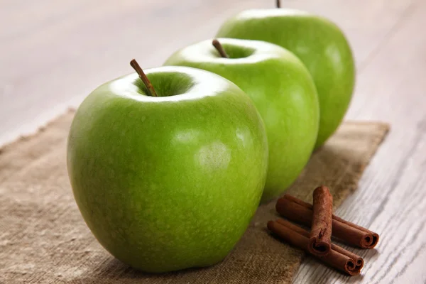 Manzanas verdes con palitos de canela en una arpillera — Foto de Stock