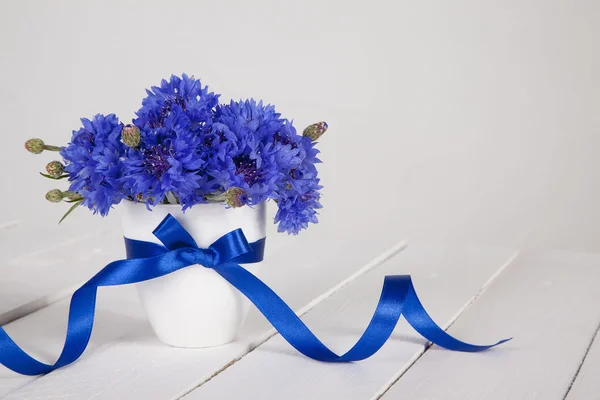 Blauwe korenbloemen in vaas met blauw lint Stockafbeelding