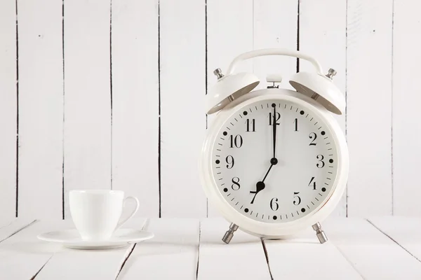 Cup of coffee and alarm clock on wooden table Royalty Free Stock Photos