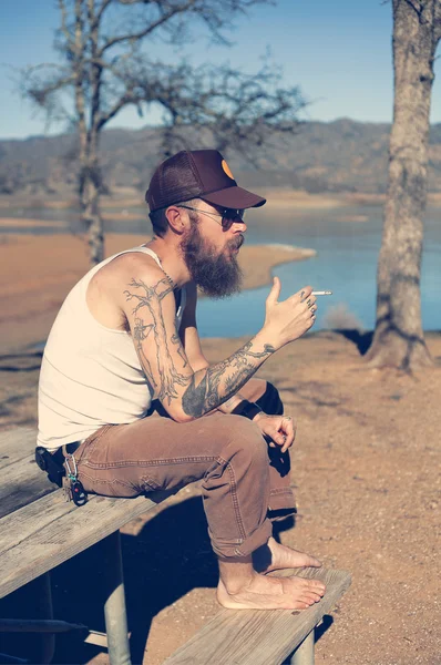 Hipster man met tatoeage rookt — Stockfoto