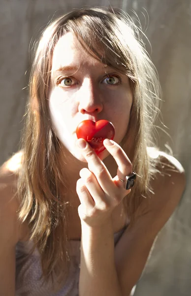 Pretty blond girl holding a heart in her hand — Stock Photo, Image