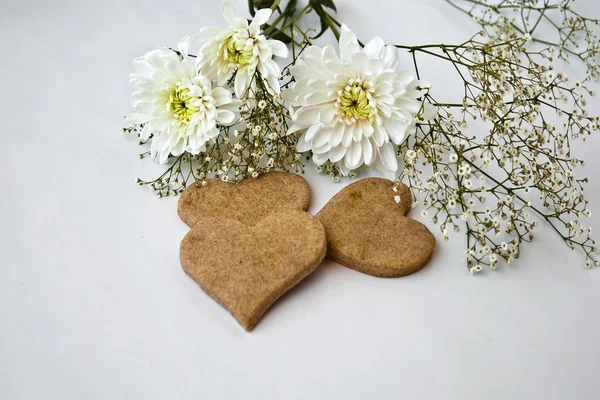 Chrysanthemen und herzförmige Kekse — Stockfoto