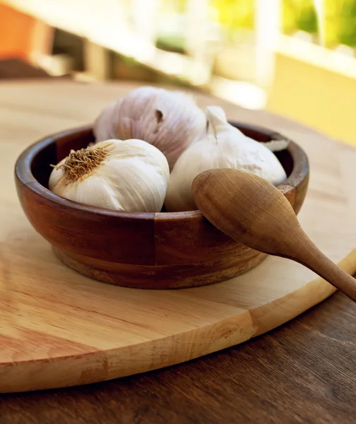 Garlic in wooden bowl with wooden spoon — Stock Photo, Image