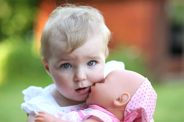 Portrait of a very cute baby girl holding a doll in her arms — Stock Photo, Image