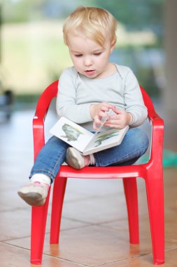kapalı bir küçük kırmızı plastik sandalye üzerinde oturan kız bebek
