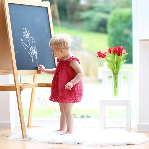 Dziewczyna rysunek tulipany kredą na czarny deska — Zdjęcie stockowe