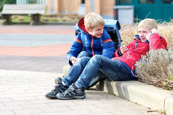 Tweeling zitten buiten de school — Stockfoto